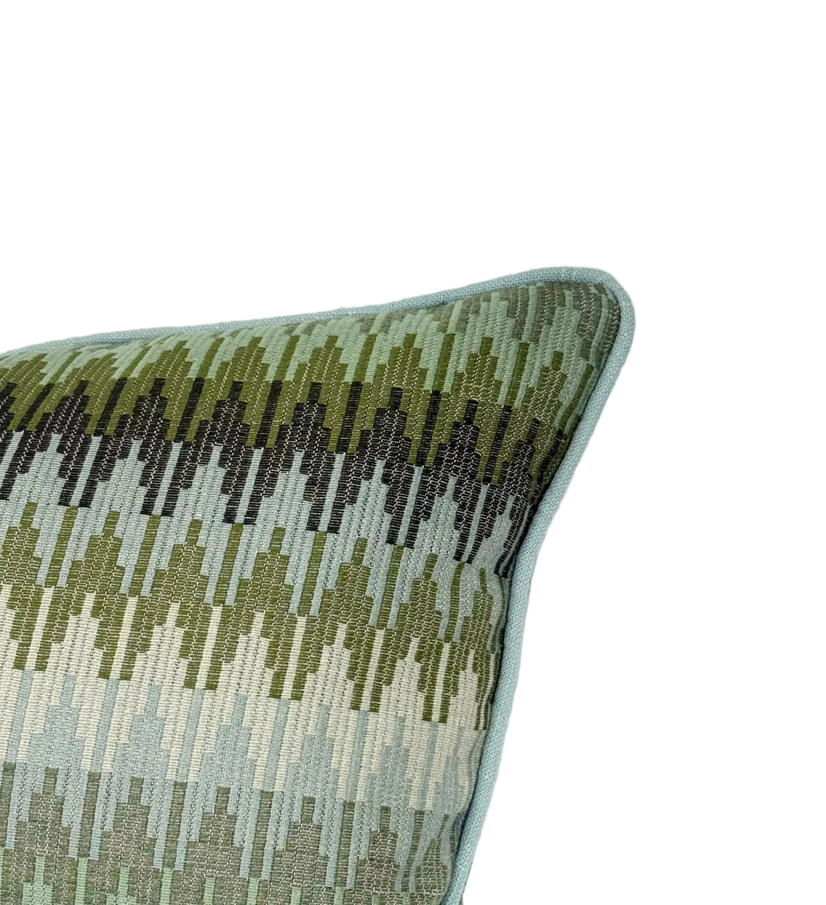 A close-up of a woven throw pillow corner showing a geometric pattern in shades of olive green, and light blue, finished with a light blue piped edge.