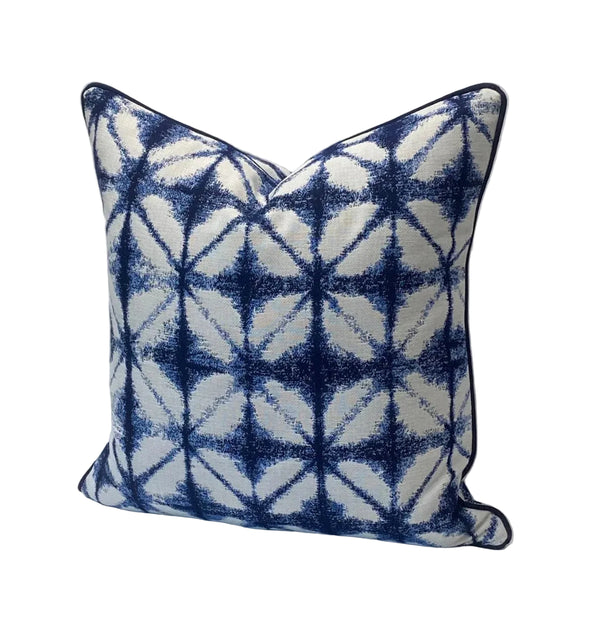 Decorative pillow with blue and white geometric pattern on a plain background