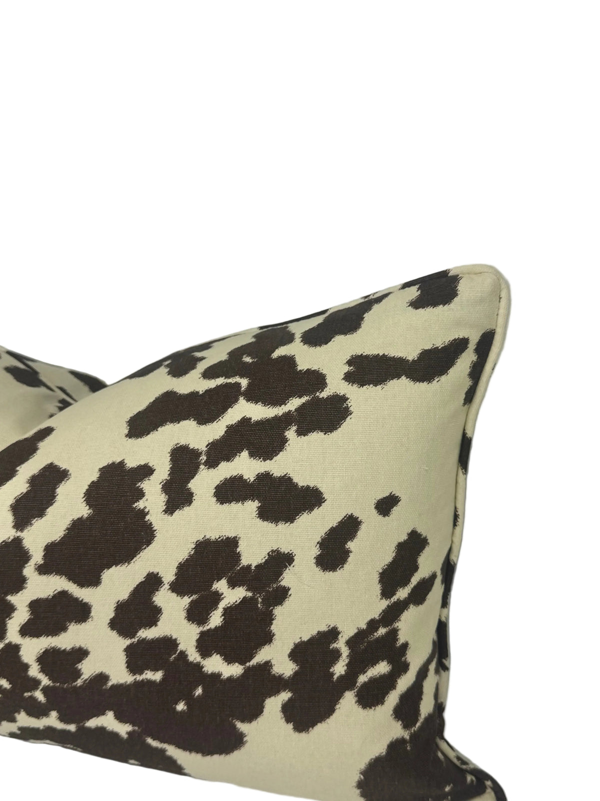 A square throw pillow with a dark brown cow-print pattern on a cream background, shown against a white backdrop.