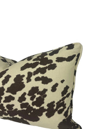 A square throw pillow with a dark brown cow-print pattern on a cream background, shown against a white backdrop.