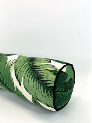 Bolster pillow with a green palm leaf pattern on a white background, presumably made of linen, with a zipper enclosure and your choice of welt/piping on one end.