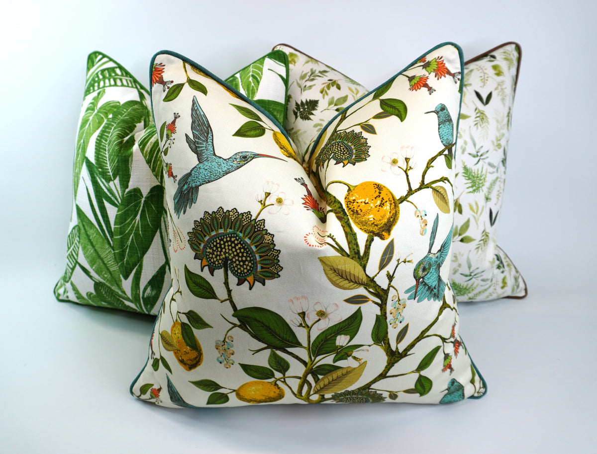 Decorative pillow with a teal hummingbird and floral pattern on a lemon tree on an Ivory-beige background (pictured with two other pillows)