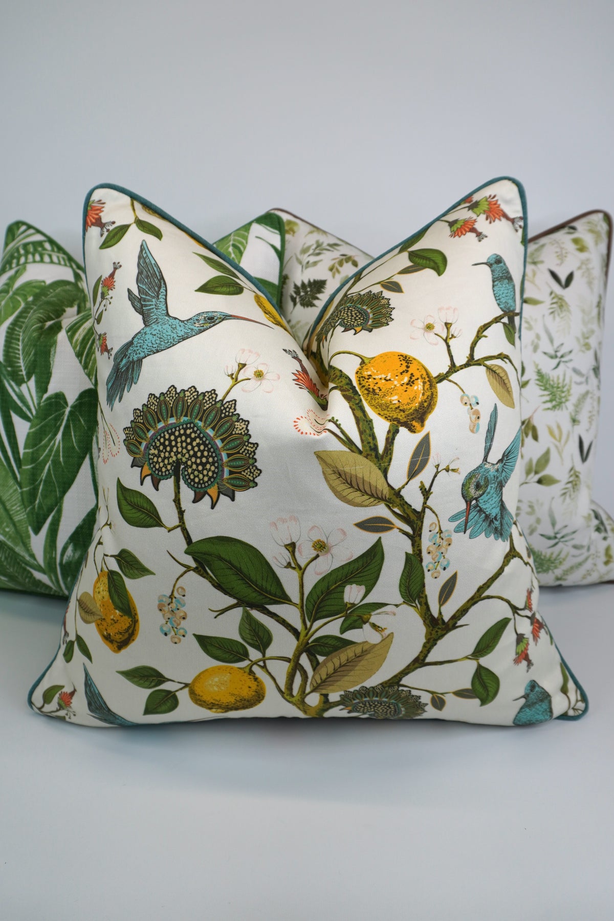 Decorative pillow with a teal hummingbird and floral pattern on a lemon tree on an Ivory-beige background