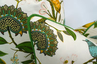 Close up of the Corner of Decorative pillow with a teal hummingbird and floral pattern on a lemon tree on an Ivory-beige background and Green Piping/Welt