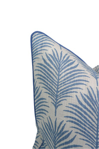 Close-up of a decorative pillow with blue palm leaf pattern on a white background