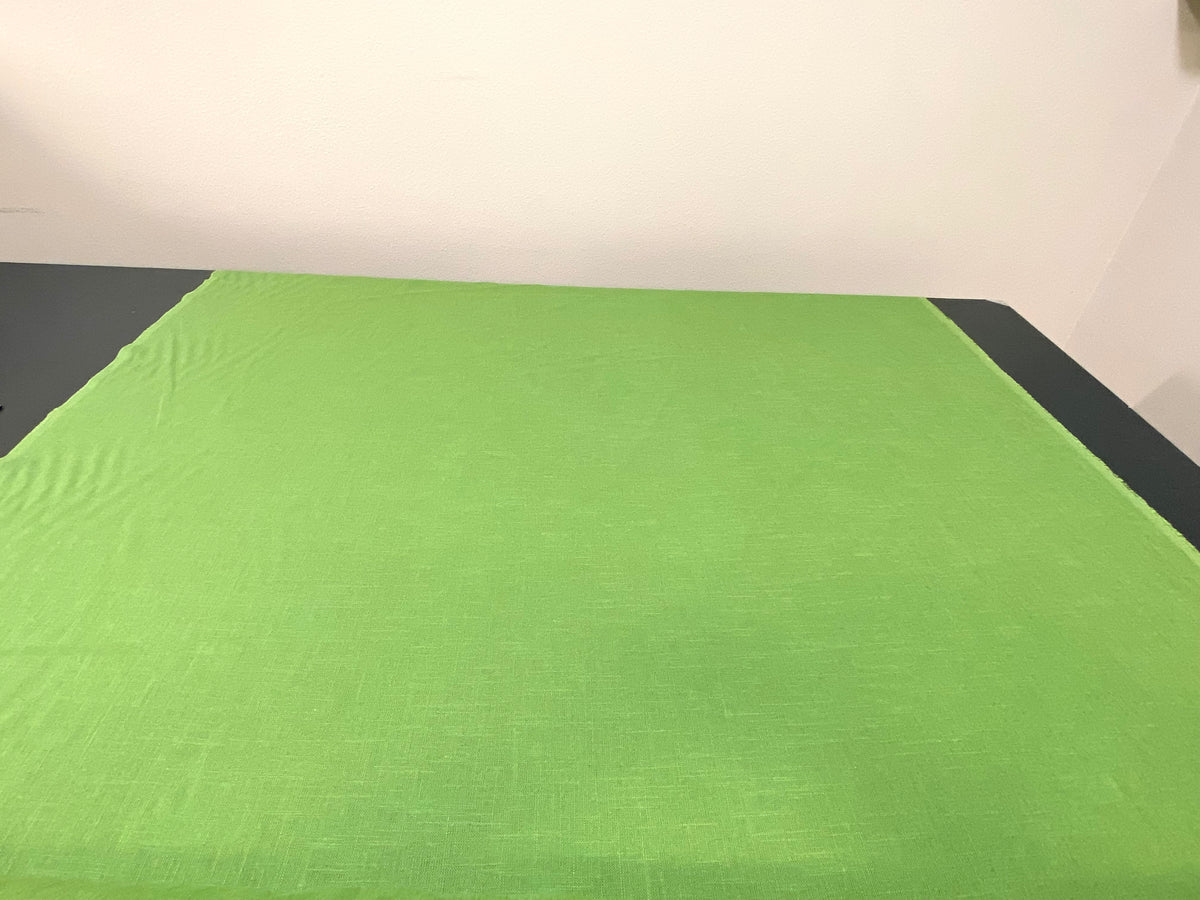 Showing Green Linen Fabric rolled out onto table.