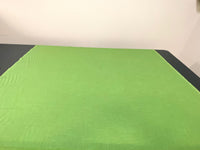Showing Green Linen Fabric rolled out onto table.