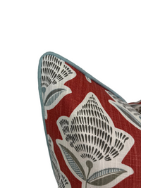 Up-close view of the Blue Welt/Piping on the Decorative pillow with light blue floral pattern on red background